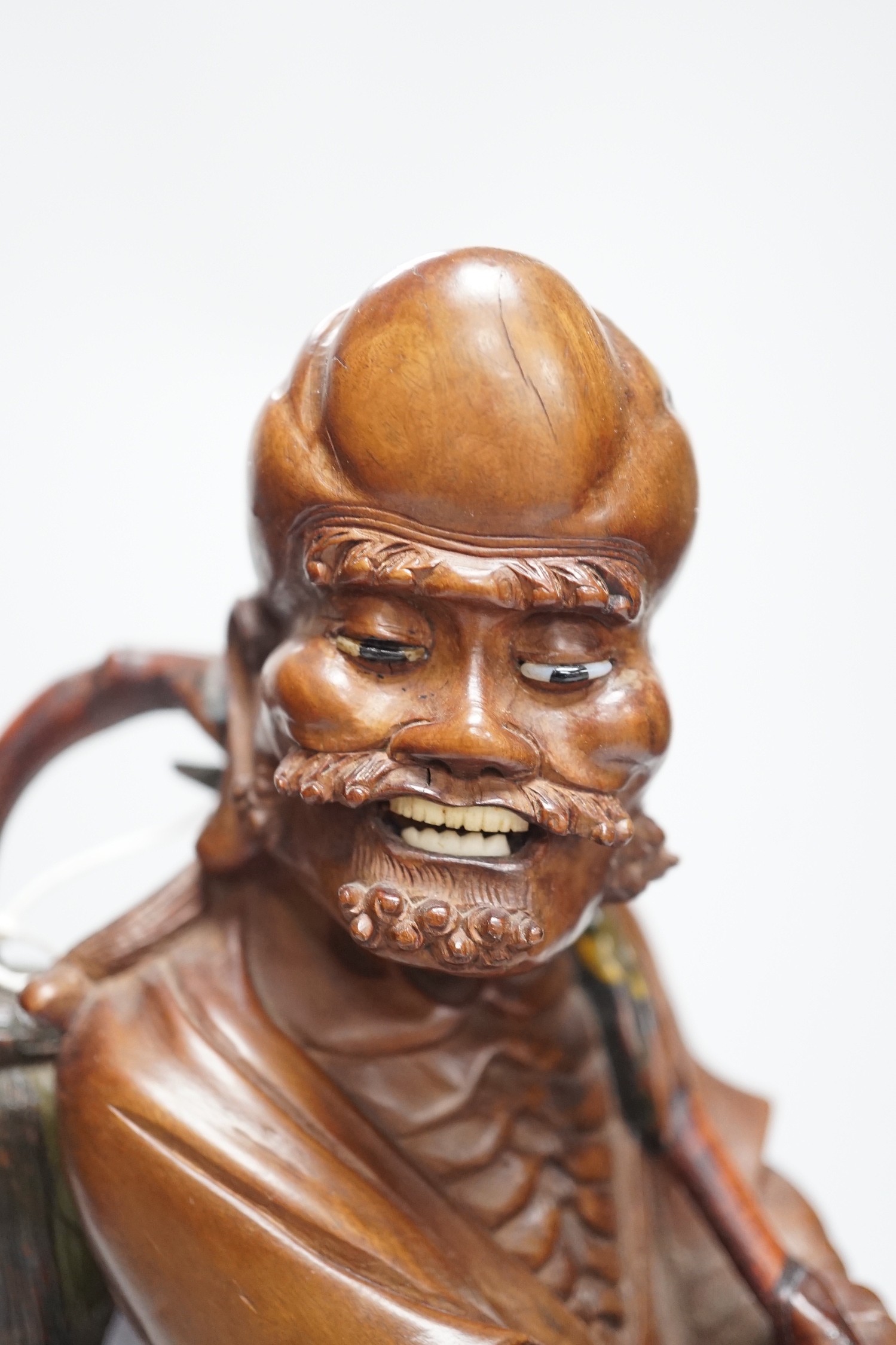 An early 20th century Chinese hardwood carving of a luohan, on soapstone base, 36cm tall